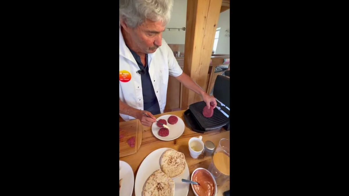 Rote KIVEGAN Burgerscheiben liegen auf einem Kontaktgrill, davor aufgeschnittene Burgerbrötchen und eine Schüssel Soße